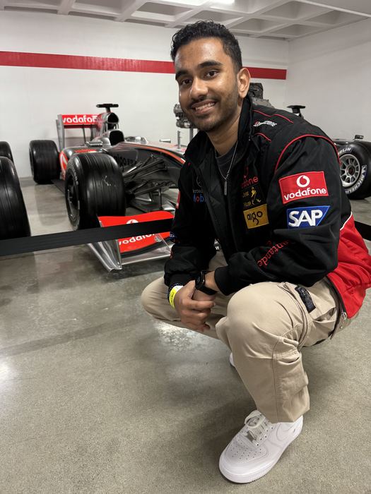 Naveen crouching beside a McLaren F1 car at the Petersen Automotive Museum